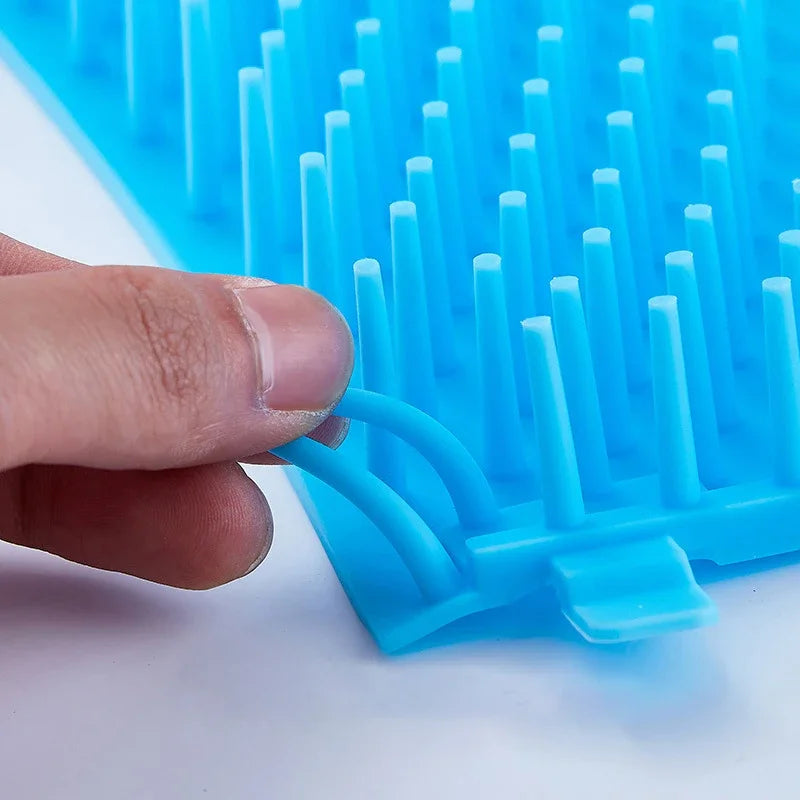 Blue soft silicone pet paw cleaner with a hand holding it on a white background