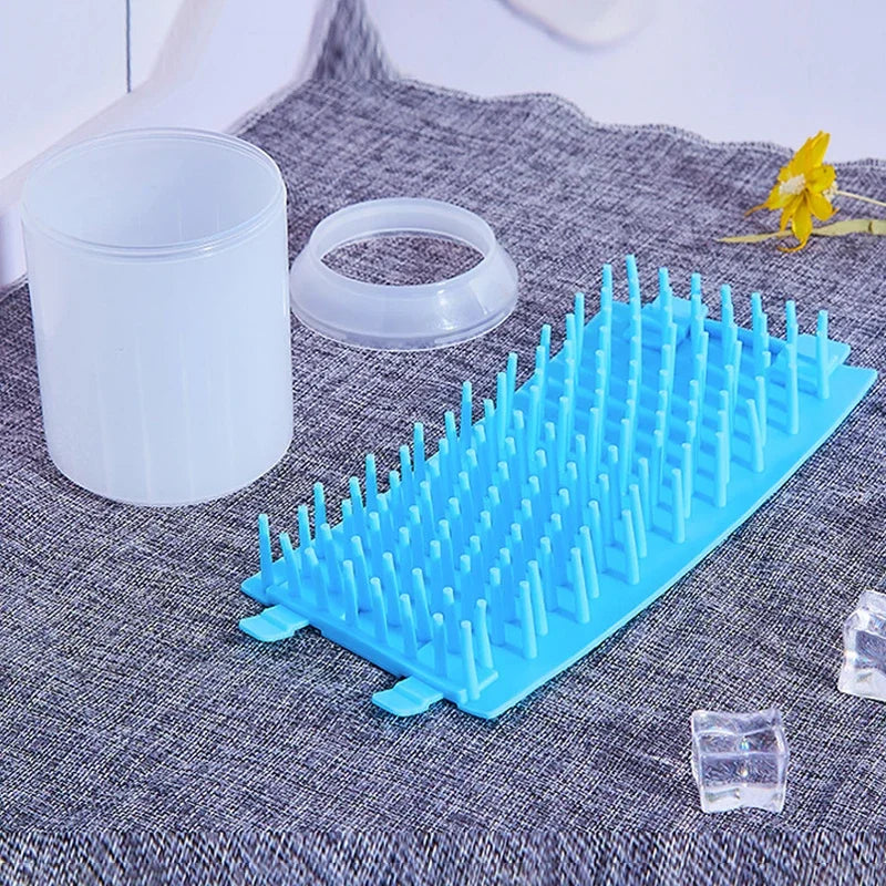 Blue soft silicone pet paw cleaner on a textured surface with a white container and clear cubes.