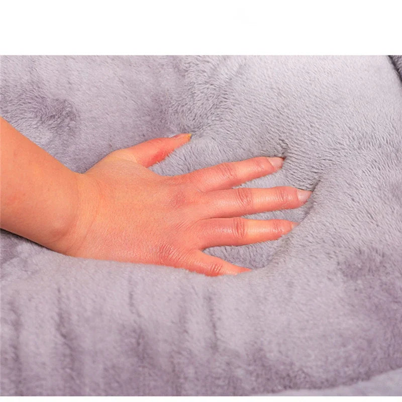 Hand placed on a soft, gray plush dog bed to show size and texture