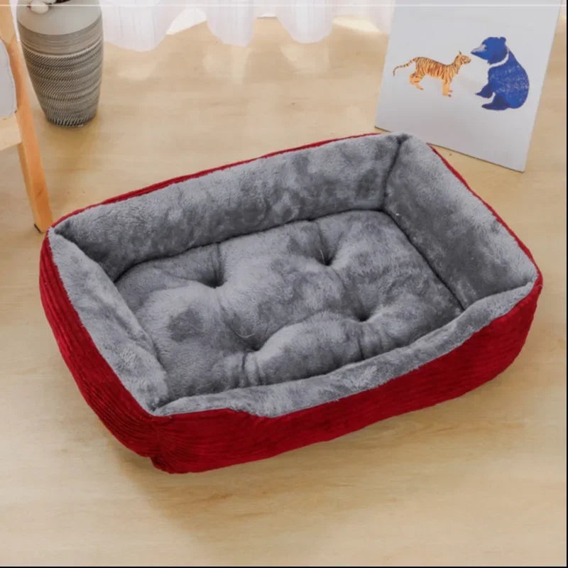 Red and gray pet bed on a wooden surface with a white card featuring animal illustrations in the background.