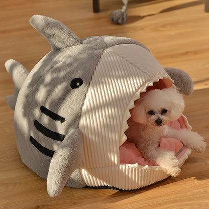 Dog in a shark-shaped pet bed on a wooden floor