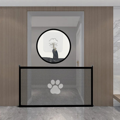 Pet gate with paw print design in a room with wooden walls and a round mirror.