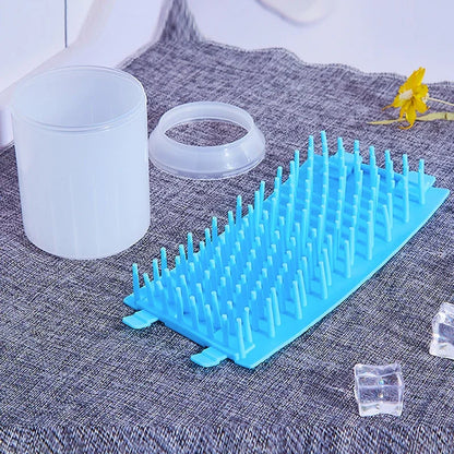 Blue soft silicone pet paw cleaner on a textured surface with a white container and clear cubes.