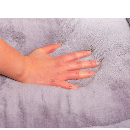 Hand placed on a soft, gray plush dog bed to show size and texture